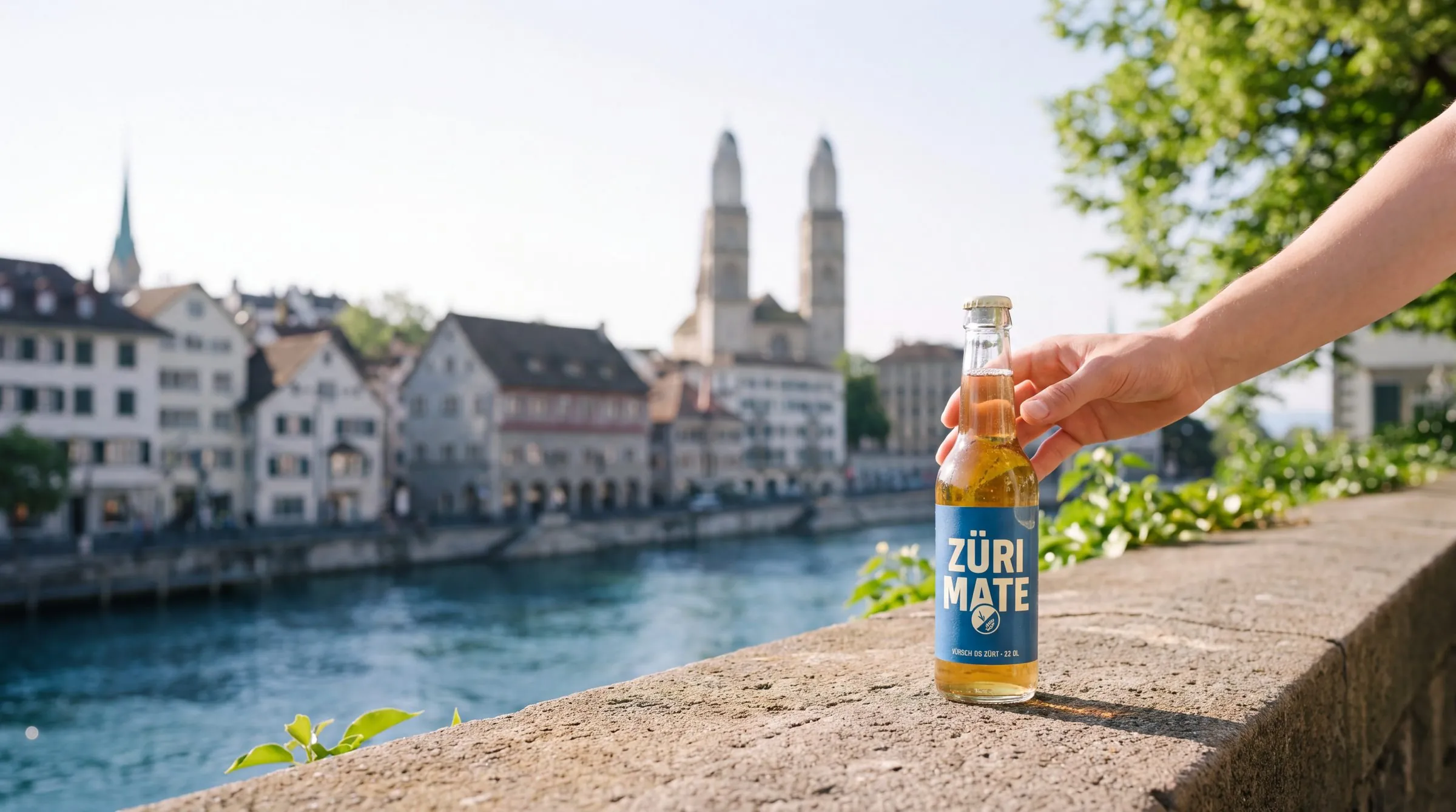Hand hält eine Flasche Züri Mate über der Limmat, im Hintergrund das Grossmünster